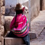 pe_al_woman in traditional clothes with lama sitting on stone in cuzco - peru.jpg