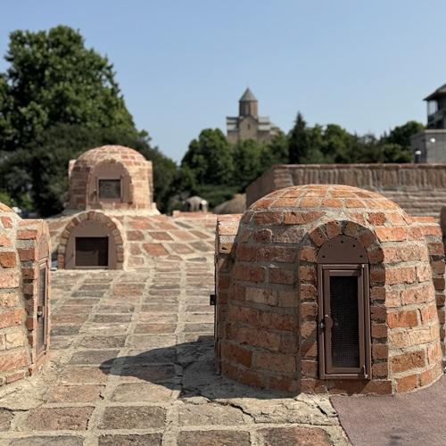 Tbilisi, daken van badhuizen in de wijk Abanotubani, met de Metekhi kerk op de achtergrond