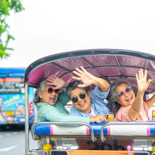 Zwaaiende Aziatische mensen in tuktuk