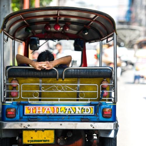 Liggende Thaise man in tuktuk in Bangkok
